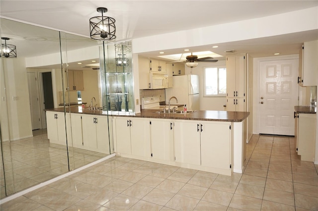 kitchen featuring white cabinetry, kitchen peninsula, pendant lighting, sink, and white appliances