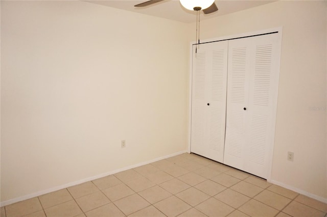 unfurnished bedroom with light tile patterned floors, ceiling fan, and a closet