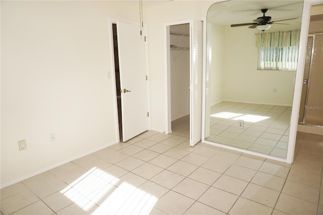 unfurnished bedroom featuring ceiling fan, light tile patterned floors, and a closet