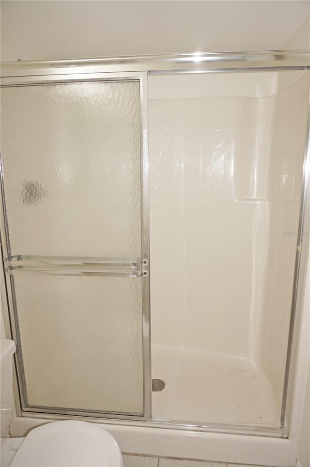 bathroom with toilet and a shower with door