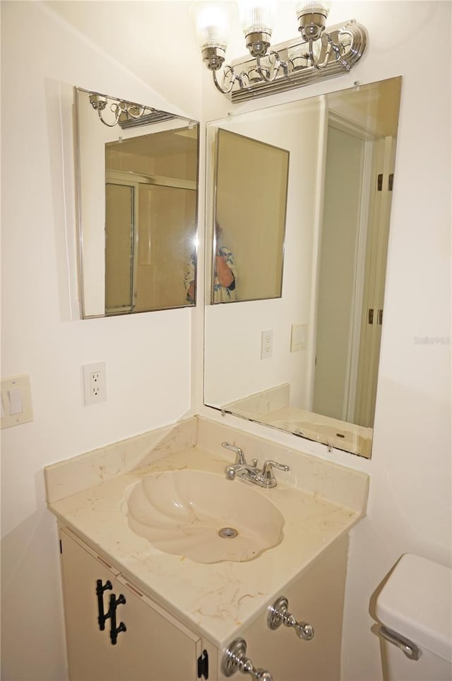 bathroom featuring vanity, toilet, and a shower with door