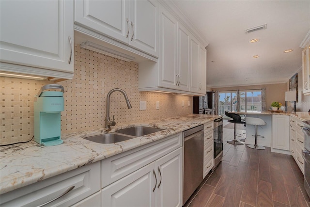 kitchen with dark wood-type flooring, sink, stainless steel dishwasher, tasteful backsplash, and white cabinetry