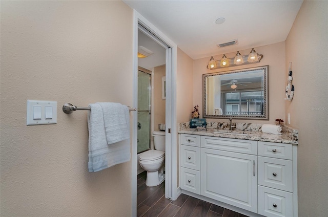 bathroom with hardwood / wood-style flooring, vanity, toilet, and a shower with door