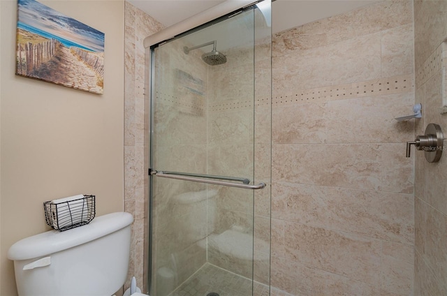 bathroom featuring toilet and a shower with shower door