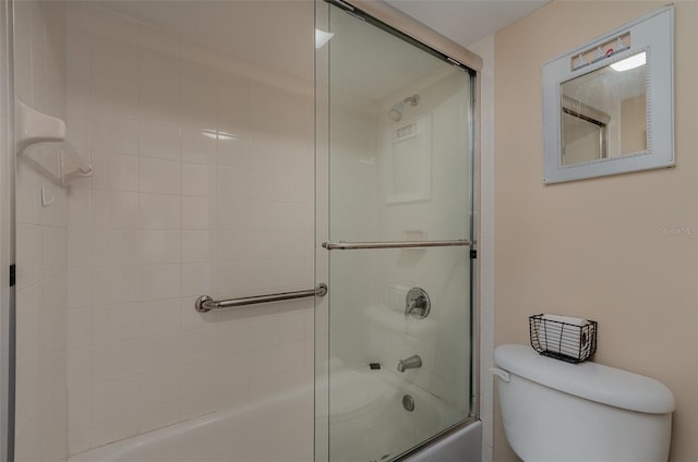 bathroom featuring toilet and shower / bath combination with glass door