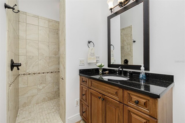 bathroom with tiled shower and vanity