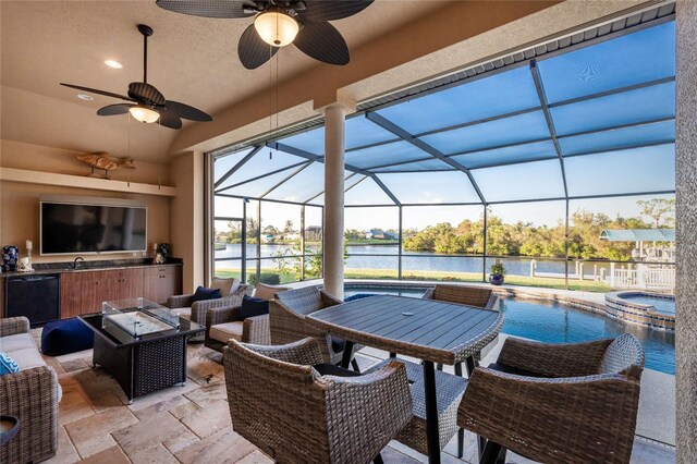 view of patio featuring glass enclosure, an outdoor kitchen, an outdoor living space, a swimming pool with hot tub, and a water view