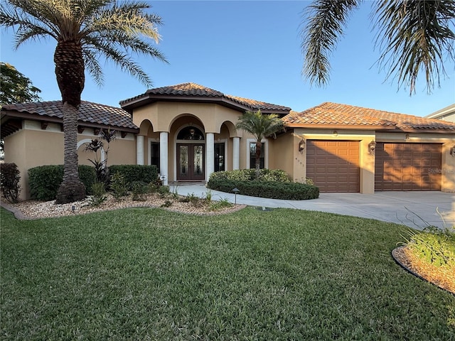 mediterranean / spanish-style house with a garage, a front yard, and french doors