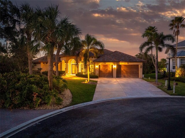 mediterranean / spanish-style house featuring a lawn and a garage