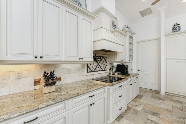 kitchen with white cabinets, black electric stovetop, ornamental molding, tasteful backsplash, and light stone counters