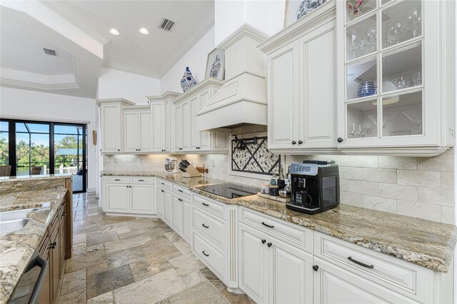 kitchen featuring light stone countertops, white cabinetry, black electric stovetop, and crown molding