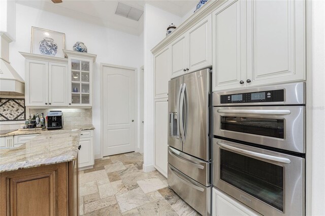 kitchen featuring white cabinets, decorative backsplash, light stone countertops, and appliances with stainless steel finishes