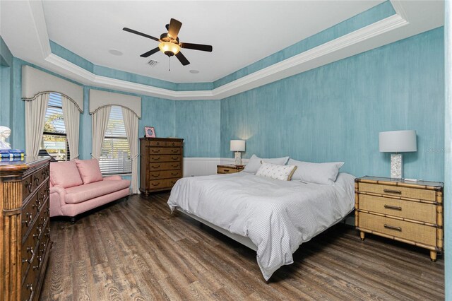 bedroom with ceiling fan, dark hardwood / wood-style flooring, and a tray ceiling