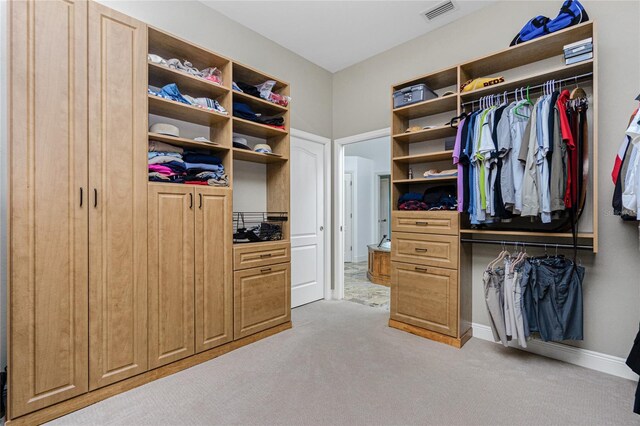 walk in closet featuring light colored carpet