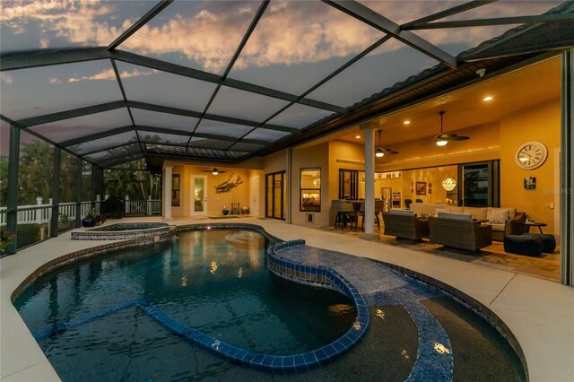 pool at dusk with outdoor lounge area, ceiling fan, a patio, and an in ground hot tub