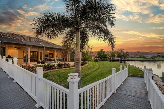 dock area with a lawn and a water view