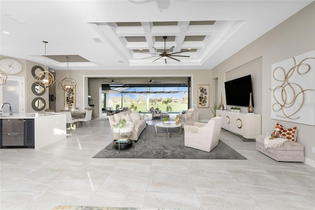 living room featuring ceiling fan with notable chandelier, a tray ceiling, beam ceiling, and coffered ceiling