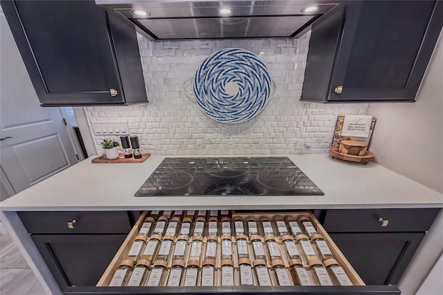 kitchen featuring range hood, tasteful backsplash, light stone counters, and black electric stovetop