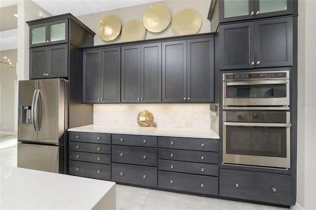 kitchen with decorative backsplash, light tile patterned floors, and stainless steel appliances