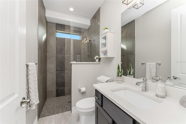 bathroom with toilet, vanity, and tiled shower