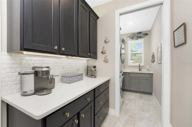 interior space featuring stacked washer and dryer, sink, and decorative backsplash