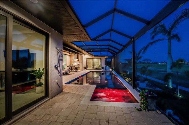 pool at twilight with a patio and a lanai