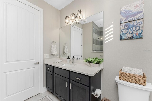 bathroom with tile patterned floors, vanity, toilet, and a tile shower