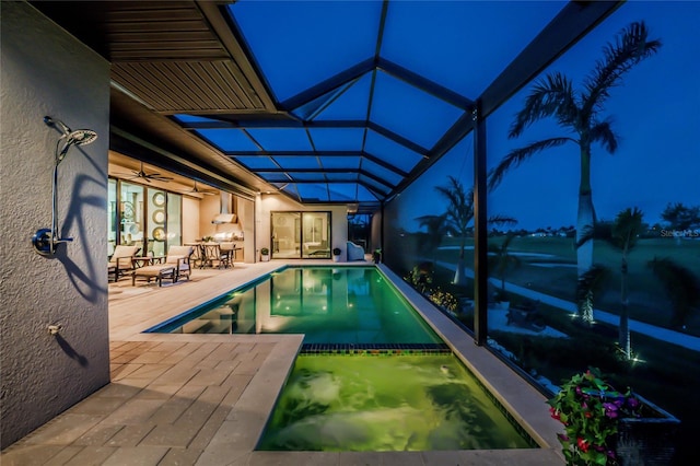 pool at twilight with a lanai and a patio area