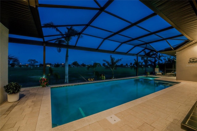 pool at dusk with a lanai and a patio area