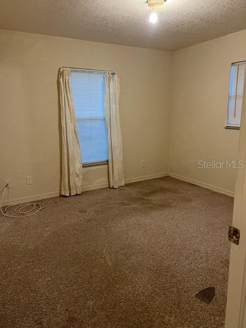 carpeted spare room featuring a textured ceiling