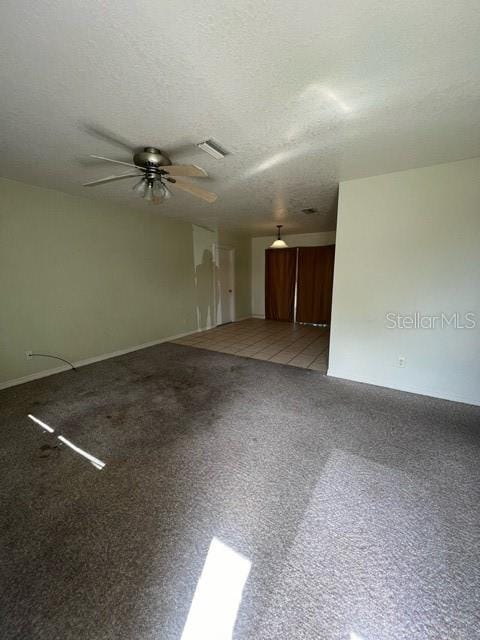 unfurnished room featuring ceiling fan, carpet floors, and a textured ceiling