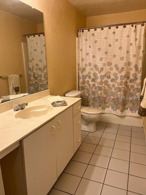 full bathroom featuring toilet, vanity, tile patterned floors, and shower / bath combo with shower curtain