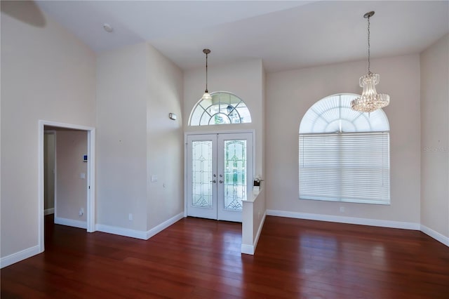 entrance foyer with dark hardwood / wood-style flooring, french doors, a towering ceiling, and a chandelier