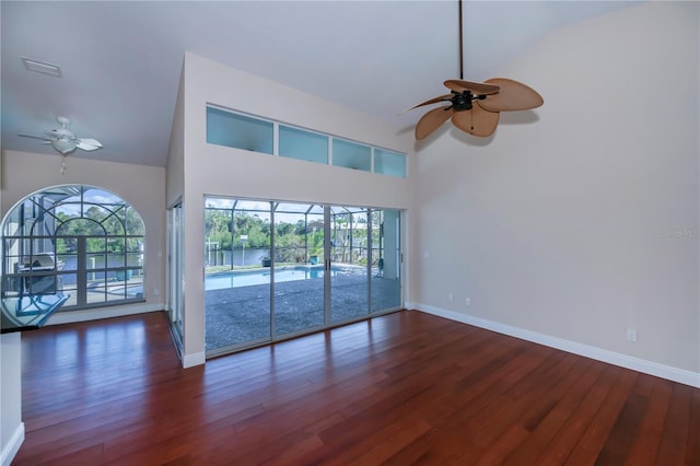 unfurnished living room with ceiling fan, high vaulted ceiling, and dark hardwood / wood-style floors