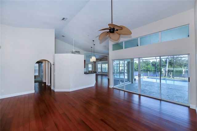 unfurnished living room featuring high vaulted ceiling, a healthy amount of sunlight, and dark hardwood / wood-style floors