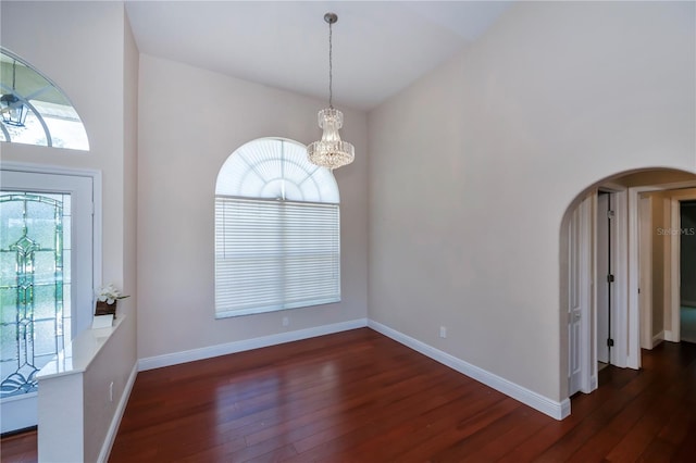 foyer with plenty of natural light, dark wood-type flooring, and an inviting chandelier