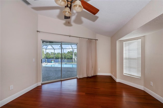 unfurnished room featuring a textured ceiling, ceiling fan, dark wood-type flooring, and vaulted ceiling