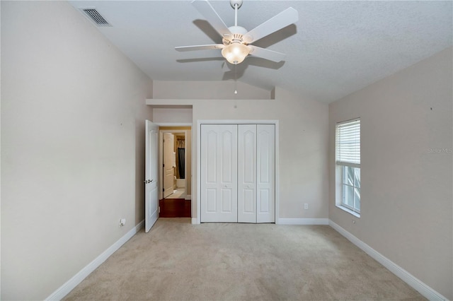 unfurnished bedroom featuring light carpet, a textured ceiling, ceiling fan, a closet, and lofted ceiling