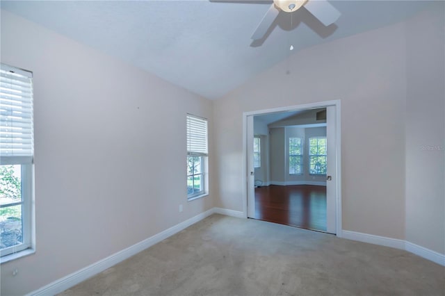 carpeted empty room with ceiling fan, a healthy amount of sunlight, and vaulted ceiling