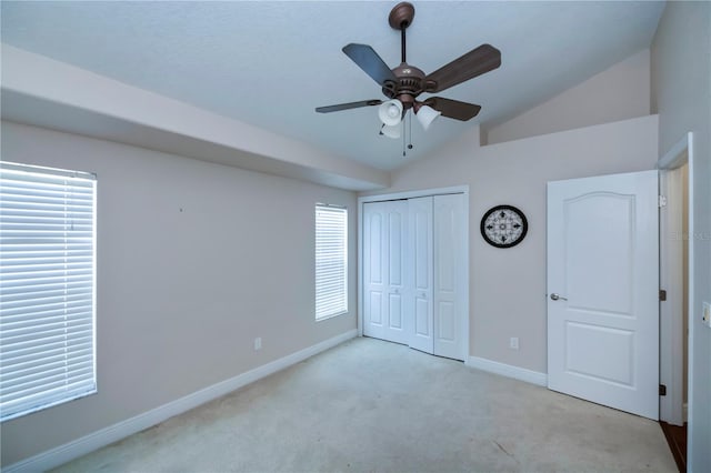 unfurnished bedroom featuring light carpet, vaulted ceiling, multiple windows, and ceiling fan