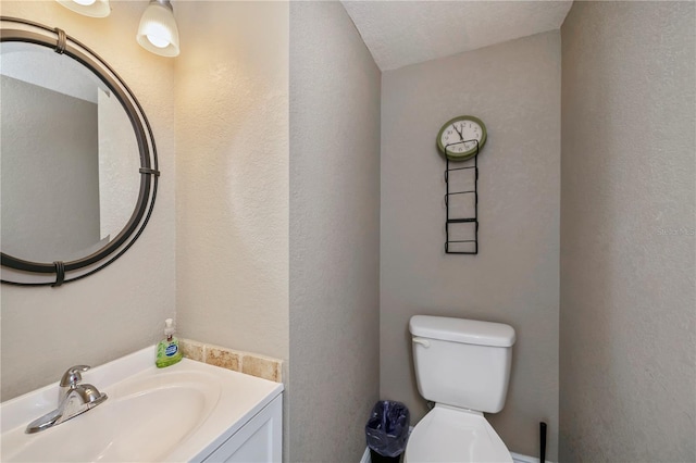 bathroom with vanity, toilet, and a textured ceiling