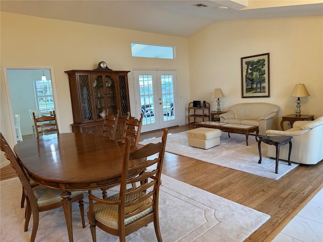 dining space with lofted ceiling, light hardwood / wood-style flooring, and french doors