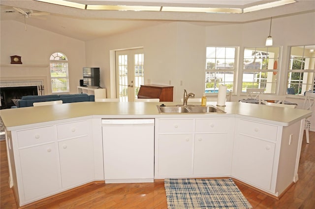 kitchen featuring white dishwasher, a wealth of natural light, sink, and an island with sink