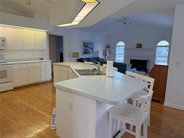 kitchen featuring white cabinetry, light wood-type flooring, sink, vaulted ceiling, and white appliances