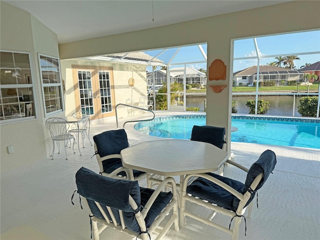 view of swimming pool with a lanai, a patio, and a water view