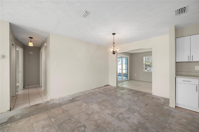 unfurnished dining area featuring a textured ceiling and a chandelier