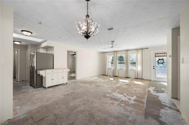 unfurnished living room with a textured ceiling and ceiling fan with notable chandelier