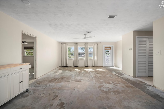 unfurnished living room with a textured ceiling and a wealth of natural light