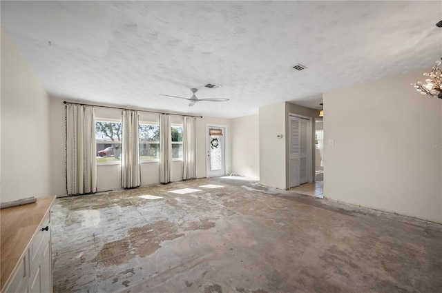 unfurnished room featuring a textured ceiling and ceiling fan with notable chandelier