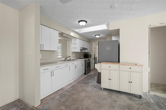 kitchen with a skylight, sink, a textured ceiling, white cabinets, and appliances with stainless steel finishes